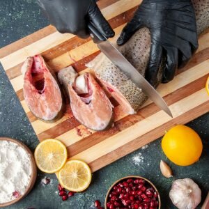top-view-cook-cutting-raw-fish-chopping-board-flour-bowl-table